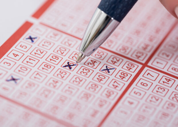 Woman Marking Number On Lottery Ticket With Pen